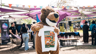 Mascota institucional (Usachín) mostrando la polera de Usach sostenible